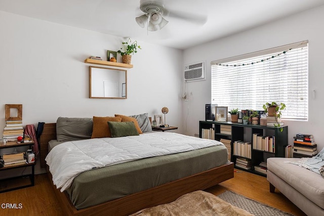 bedroom featuring a wall mounted AC and wood finished floors