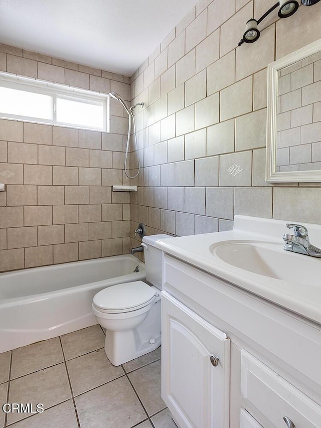 bathroom featuring shower / bath combination, toilet, tile patterned flooring, vanity, and tile walls