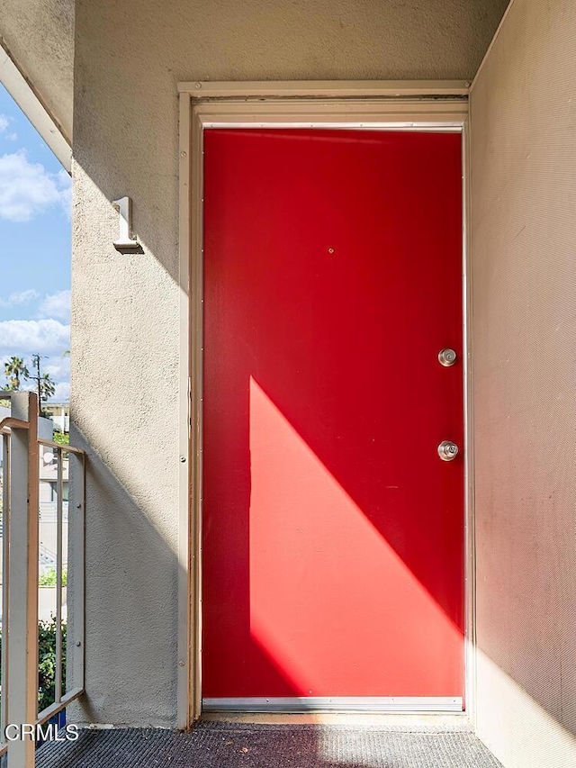 entrance to property with a balcony and stucco siding