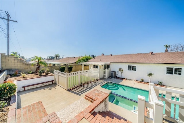 view of swimming pool with a patio area, a fenced backyard, a pool with connected hot tub, and central AC