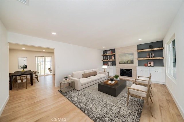 living area with recessed lighting, a fireplace, light wood-style flooring, and baseboards