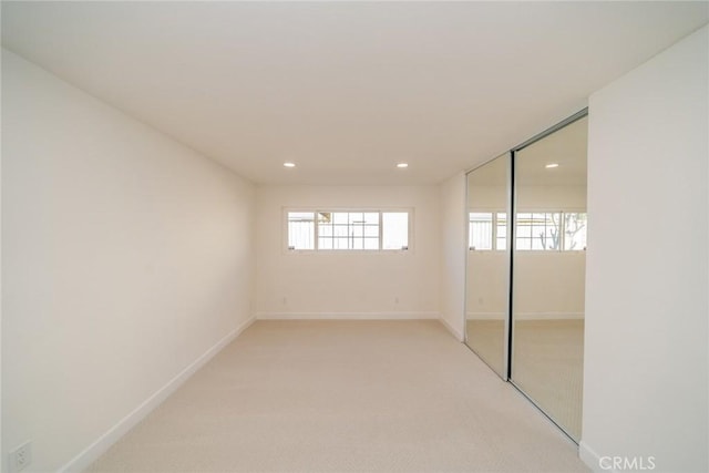 unfurnished bedroom with recessed lighting, a closet, light carpet, and baseboards