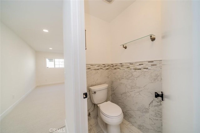 bathroom featuring toilet, recessed lighting, a wainscoted wall, tile walls, and marble finish floor