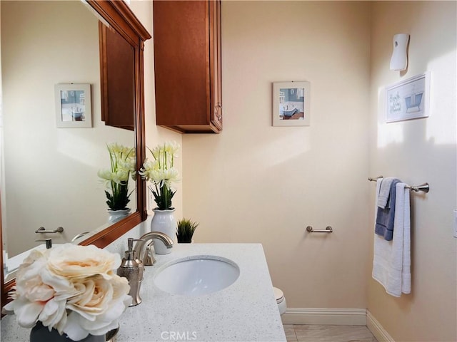 bathroom with toilet, baseboards, and a sink