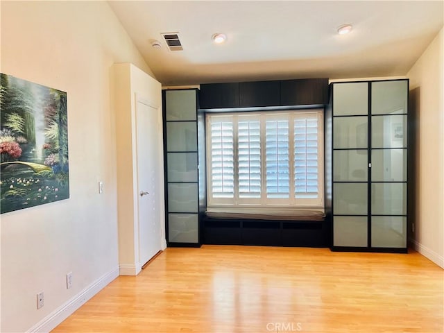 unfurnished room with baseboards, visible vents, and wood finished floors