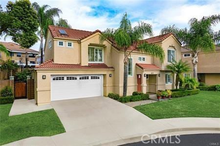 mediterranean / spanish home with driveway, a tiled roof, an attached garage, a front lawn, and stucco siding