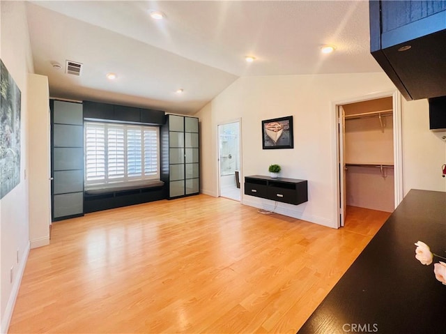 unfurnished living room with lofted ceiling, baseboards, visible vents, and light wood-style floors