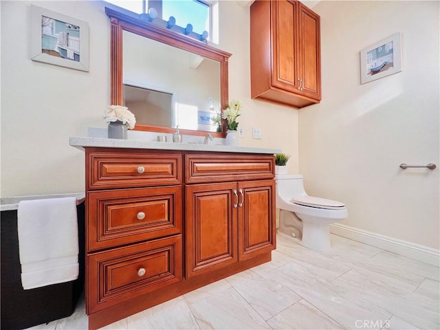 bathroom featuring toilet, baseboards, and vanity