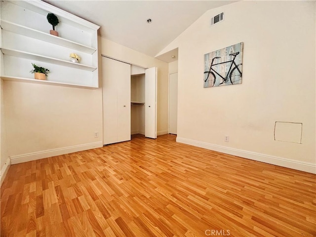 unfurnished bedroom with lofted ceiling, baseboards, visible vents, and light wood-style floors