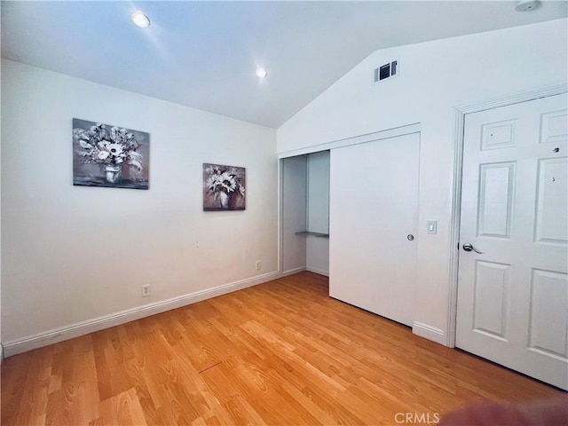 unfurnished bedroom with lofted ceiling, visible vents, baseboards, a closet, and light wood finished floors