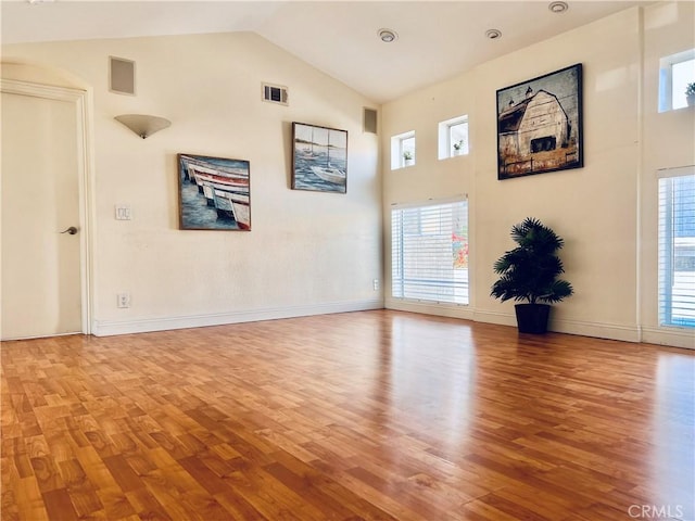 spare room with visible vents, high vaulted ceiling, wood finished floors, and a wealth of natural light