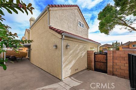 view of side of property with a tiled roof, fence, a gate, and stucco siding