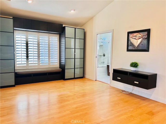 unfurnished room with lofted ceiling, wood finished floors, and baseboards