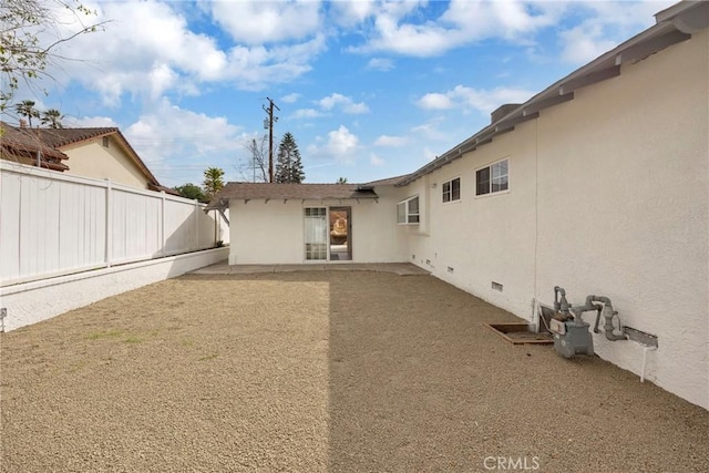 rear view of house featuring crawl space, fence, a patio, and stucco siding