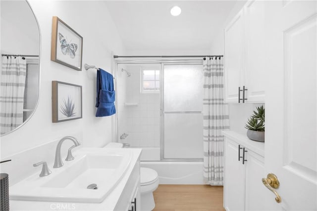 full bathroom with toilet, shower / tub combo, wood finished floors, and vanity