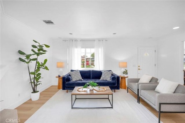 living area featuring light wood finished floors, visible vents, and baseboards