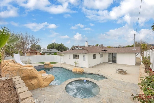 view of swimming pool featuring an outdoor fire pit, a patio area, an in ground hot tub, a water slide, and a fenced backyard