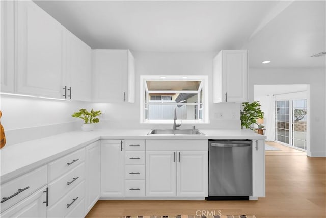 kitchen featuring visible vents, light countertops, stainless steel dishwasher, white cabinetry, and a sink