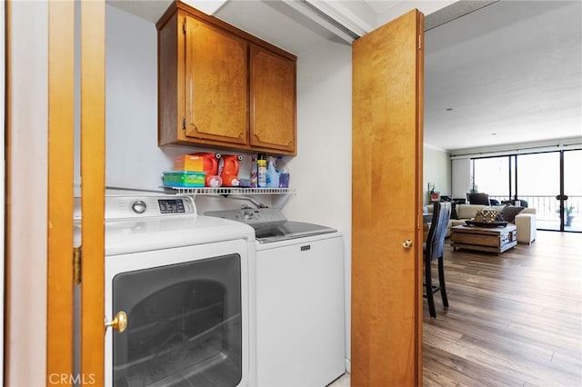 clothes washing area featuring light wood finished floors, cabinet space, and independent washer and dryer