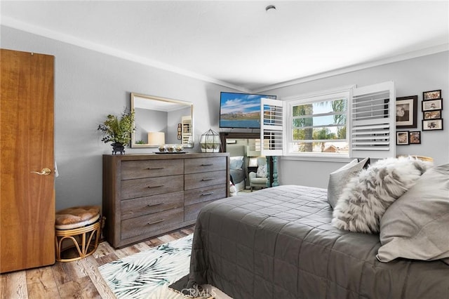 bedroom with ornamental molding and wood finished floors