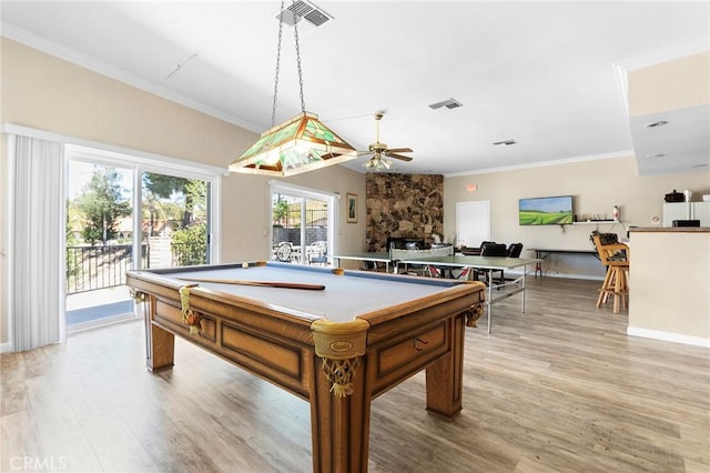 rec room featuring a stone fireplace, visible vents, crown molding, and light wood-style flooring