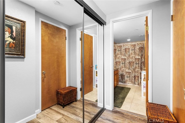 corridor with light wood-type flooring and baseboards