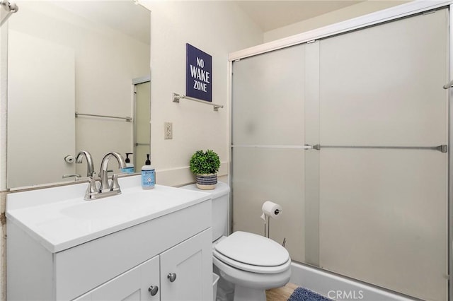 bathroom with a stall shower, vanity, and toilet