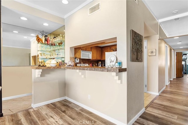 22570 Bass Pl Unit 7, Canyon Lake, CA 92587 - kitchen with white microwave, visible vents, light wood finished floors, and a breakfast bar