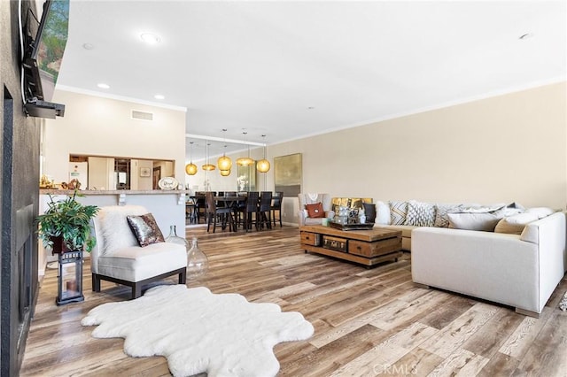 living area featuring ornamental molding, recessed lighting, visible vents, and wood finished floors