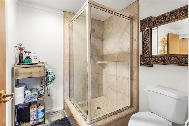 bathroom with a stall shower, toilet, and tile patterned floors