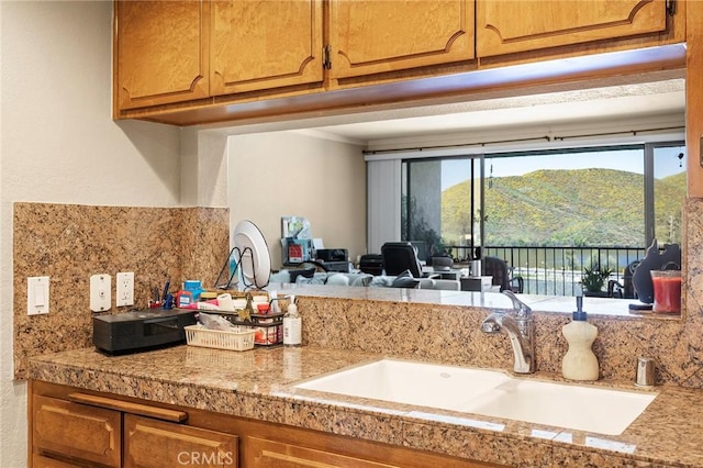 kitchen with tile countertops, tasteful backsplash, brown cabinets, and a sink