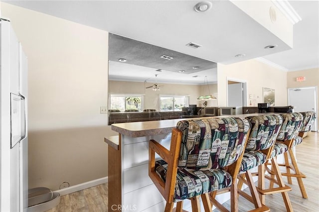 kitchen featuring visible vents, ornamental molding, light wood-style flooring, and baseboards