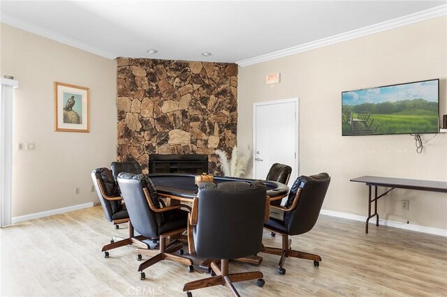 home office featuring baseboards, wood finished floors, crown molding, and a stone fireplace