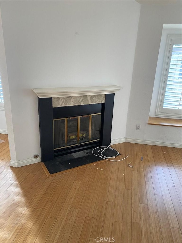 interior details with wood finished floors, a fireplace with flush hearth, and baseboards