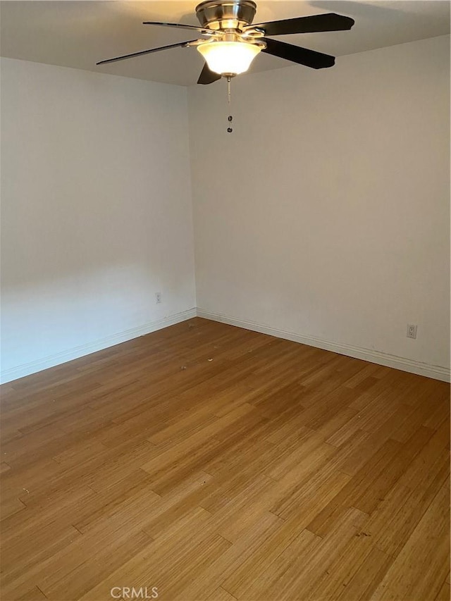 spare room featuring light wood-style floors, ceiling fan, and baseboards