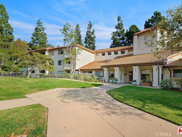 view of property's community featuring a lawn and fence