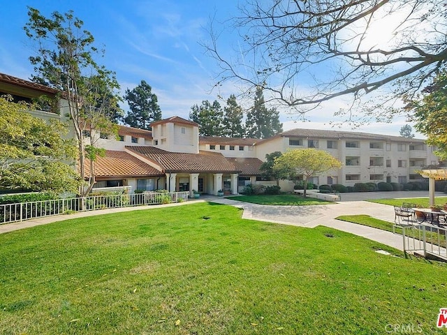 exterior space featuring driveway, a front yard, a tile roof, and fence