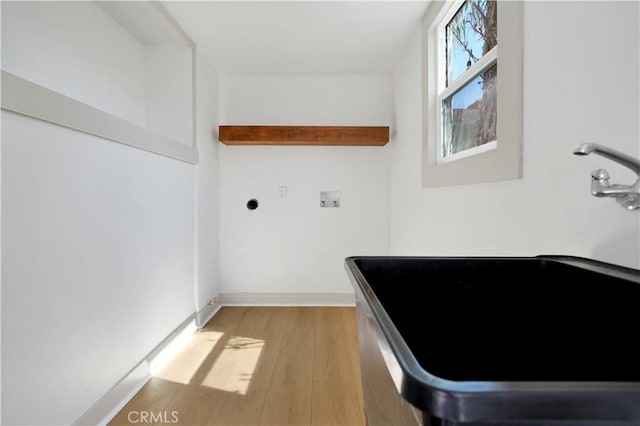 washroom with light wood finished floors, hookup for a washing machine, a sink, laundry area, and baseboards