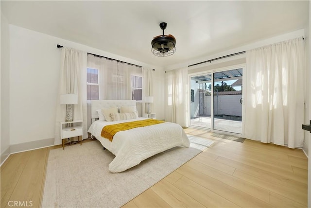 bedroom featuring baseboards, wood finished floors, and access to exterior