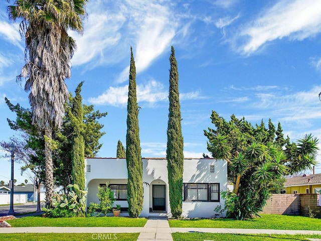 view of front of property with a front yard, fence, and stucco siding