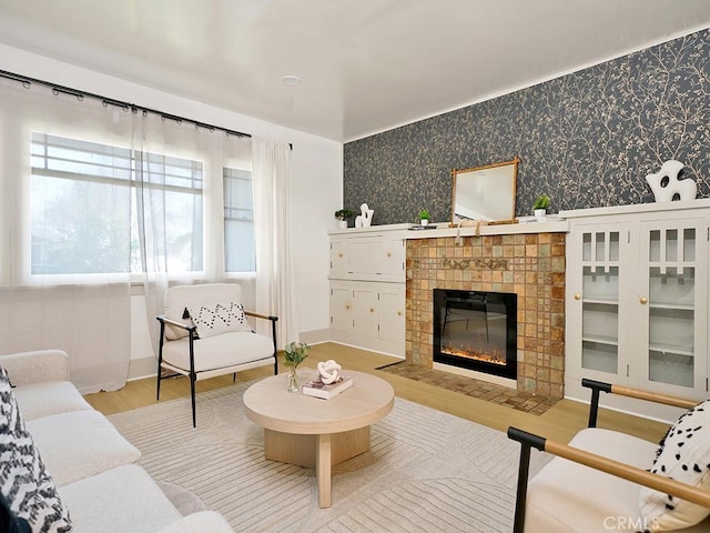 living area featuring wood finished floors, a fireplace, baseboards, and wallpapered walls