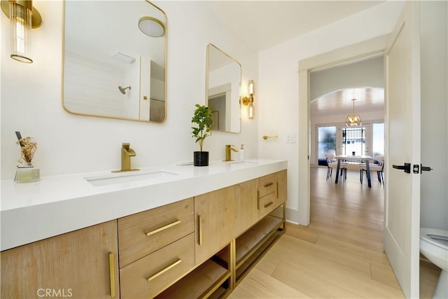 full bathroom with double vanity, a sink, toilet, and wood finished floors