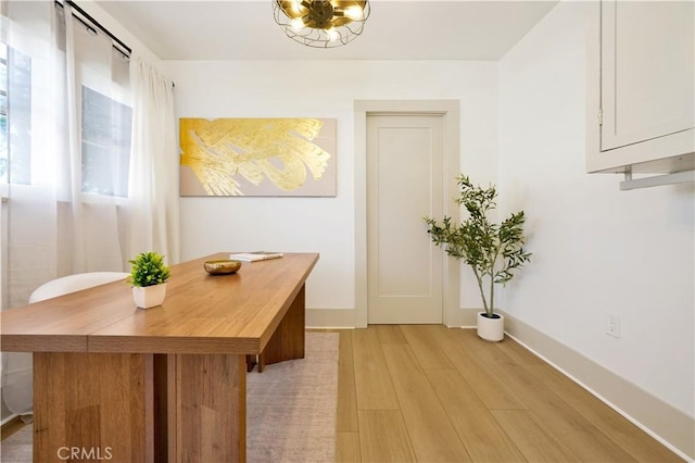 hall featuring light wood-style flooring and baseboards