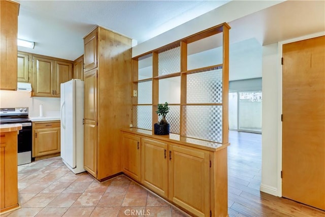 kitchen featuring light countertops, electric range, exhaust hood, and freestanding refrigerator