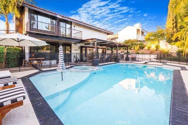 view of pool featuring a patio area, a pool with connected hot tub, and fence