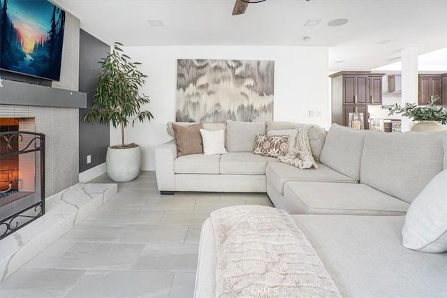 living area featuring a fireplace, baseboards, and ceiling fan