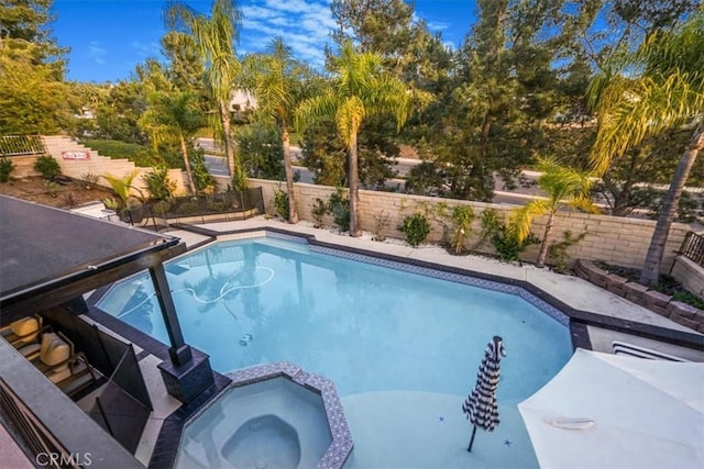 view of pool featuring a pool with connected hot tub and a fenced backyard