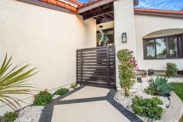 view of exterior entry featuring a tiled roof and stucco siding