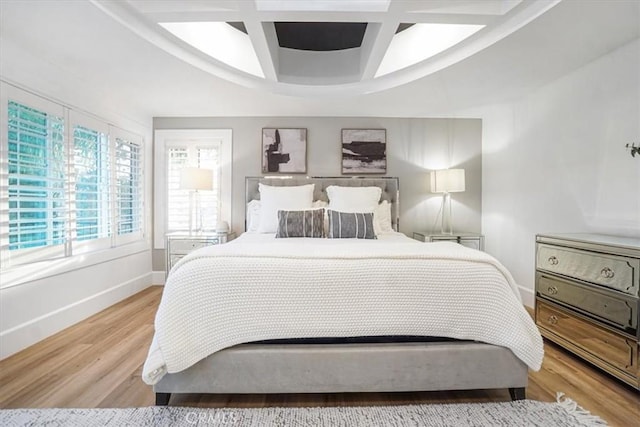 bedroom with light wood finished floors, coffered ceiling, and baseboards