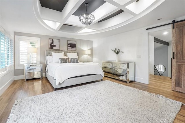 bedroom with a barn door, baseboards, coffered ceiling, wood finished floors, and a notable chandelier